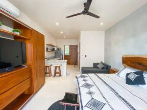 een slaapkamer met een bed en een flatscreen-tv bij BohoChic Studio with Full Kitchen, Pool, Balcony WiFi in Tulum