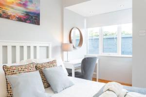 - une chambre blanche avec un lit, un bureau et des fenêtres dans l'établissement Beautiful Cottage Central Location Fast WIFI n TV, à Dublin