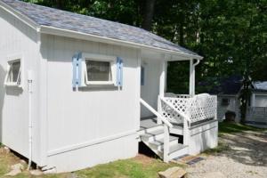a white shed with a porch and a chair at 2 River Road Inn Cottages in Cape Neddick +25 photos