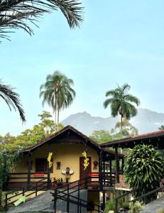 una casa con palme e montagne sullo sfondo di Pousada Doce Mel a Penedo