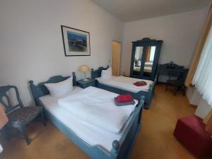 1 dormitorio con 2 camas, silla y espejo en Hotel Waldhaus Prieros, en Prieros