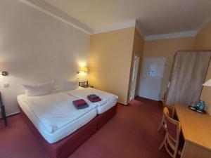 a hotel room with a bed with two red folders on it at Hotel Waldhaus Prieros in Prieros