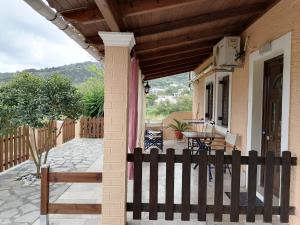 un porche de una casa con una valla de madera en Marilena's Beach House en Agios Georgios Pagon