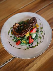 ein Teller mit Essen mit einer Wurst auf einem Salat in der Unterkunft Seconda Stella in Jambiani