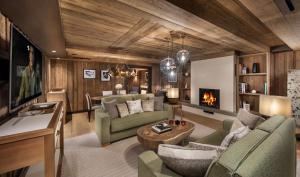 a living room with green furniture and a fireplace at Hôtel Barrière Les Neiges Courchevel in Courchevel
