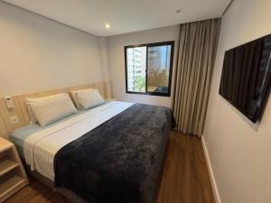 a bedroom with a large bed with a window at Flat- mercure c/ quarto, sala e coz - Moema in São Paulo