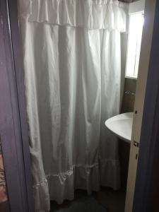 baño con cortina de ducha blanca y lavamanos en Departamento Manamar en Mar del Plata