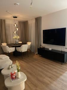 a living room with a table and a large television at KG Apartment in Hannover