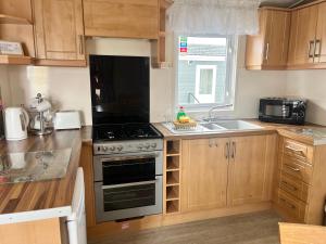 a kitchen with a stove top oven next to a sink at 3 Bedroom Self Catering Static Caravan in Steps