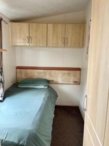 a bed in a small room with wooden cabinets at 3 Bedroom Self Catering Static Caravan in Steps