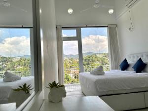 een witte slaapkamer met 2 bedden en een groot raam bij Secret Heaven Kandy in Kandy