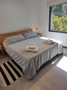 1 dormitorio con 1 cama con 2 toallas en Depto moderno con estacionamiento/ AlquilaMiCasa en San Martín de los Andes