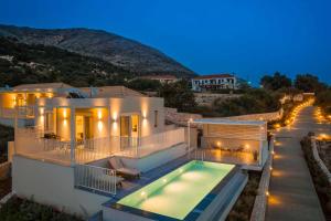 a villa with a swimming pool at night at Ostria Villa in Divarata