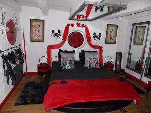 1 dormitorio con 1 cama grande con colcha roja en DOL' IN LOVE Love room BDSM 4 étoiles en Dol-de-Bretagne