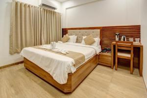 een slaapkamer met een groot bed en een bureau bij HOTEL EVERSHINE in Rajkot