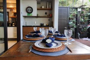 una mesa de madera con platos y copas de vino. en Condomínio Quinta de Juquehy - Prime Experience en Juquei