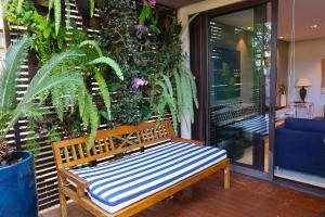 un banco de madera sentado en un porche con plantas en Condomínio Quinta de Juquehy - Prime Experience en Juquei