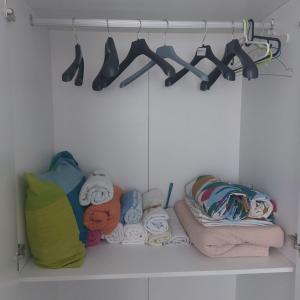 un armario con toallas y zapatos en un estante en Habitación en Sevilla dias/semana, en Camas