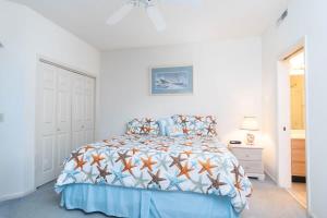 a white bedroom with a bed with a blue comforter at Tidewater- Teal lake #2521 in North Myrtle Beach