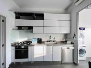 a kitchen with white cabinets and a sink and a dishwasher at Gorgeous 3Br Achrafieh Apt in Beirut