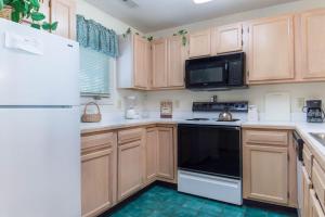 a kitchen with wooden cabinets and a black and white appliance at Tidewater Teal Lake 1323 in North Myrtle Beach