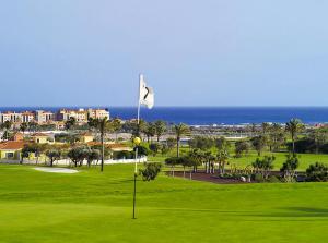 un campo de golf con bandera blanca y el océano en Villa Azure, en Caleta de Fuste