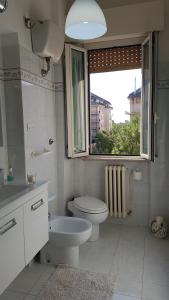 a white bathroom with a toilet and a window at Il Nido di Pikki in Falconara Marittima