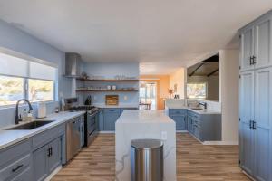 a large kitchen with blue cabinets and a sink at Jellystone Lodge- Park Adjacent w Hot and Cold Tub in Yucca Valley