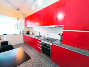 a red kitchen with a sink and red cabinets at Apartamento Esposende Quinta da Barca in Barca do Lago