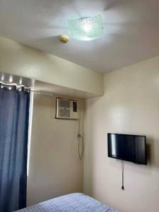 1 dormitorio con techo, TV y cama en 1-Bedroom IT Park Avida Cebu, en Cebú