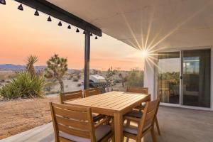 uma mesa de madeira e cadeiras no alpendre de uma casa em Kinetic House-Joshua Trees Sculptures Cowboy Pool em Yucca Valley