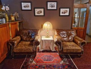 two leather chairs and a table with a lamp in a living room at ROMANTIK HOTEL ELEONORA in Tábor