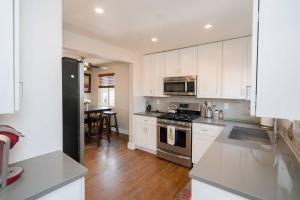 uma cozinha com armários brancos e electrodomésticos de aço inoxidável em 4-Bed Gem near Sloan's Lake em Denver