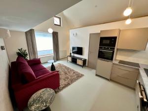 a living room with a red couch and a kitchen at Apartmán Vinařství Eisgrub in Lednice