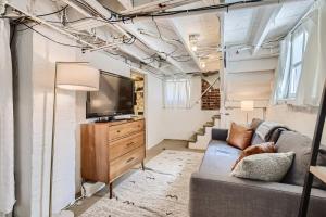 a living room with a couch and a tv at Redbrick Cottage 2BDRM Wash Park Yard & Gym in Denver