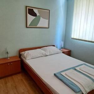 - une chambre avec un lit et une photo sur le mur dans l'établissement Apartmani ROKO, à Neum