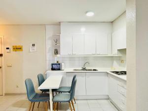 een keuken met witte kasten en een tafel en stoelen bij ROC MAR 3 3B - Apartamento cerca del centro y de la playa - terraza con vistas al mar y al puerto in Roses