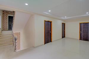 Pokój z białymi ścianami i drewnianymi drzwiami w obiekcie Super OYO Flagship 80823 Hotel Sitara Grand w mieście Visakhapatnam