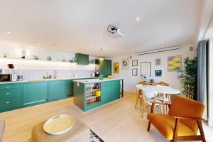 a kitchen with green cabinets and a table and chairs at 2Bed Flat w Lift & Balcony -10min to Tube Station in London