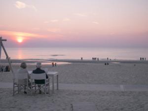deux personnes assises sur des chaises regardant le coucher de soleil sur la plage dans l'établissement Villa aan Zee, à Noordwijk