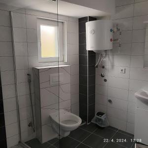 a bathroom with a toilet and a window at Apartman Numero Uno in Vogošća