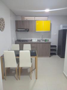 a kitchen with a dining table and white chairs at Sachar Lodging Apartahotel in Bucaramanga