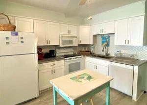 a kitchen with white cabinets and a table and a white refrigerator at The Sea Shed- Ocean Front Condo in Myrtle Beach