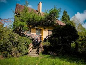 a yellow house with stairs leading up to it at W Ogrodzie Dla Gości in Sasino