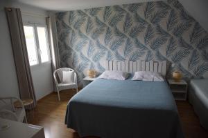 a bedroom with a bed with a blue and white patterned wall at LE SECHOIR DANTAN in Doudeville