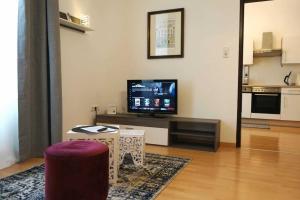 ein Wohnzimmer mit einem TV und einem Tisch mit einem Stuhl in der Unterkunft Serenity Apartment 45m2 Free Parking in Leoben