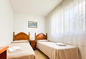 two beds in a room with a window at Acogedor apartamento cerca de la playa wifi y parking in Montroig