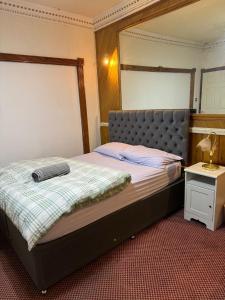 a bedroom with a bed with a headboard and a table at Crete Room in Oldham