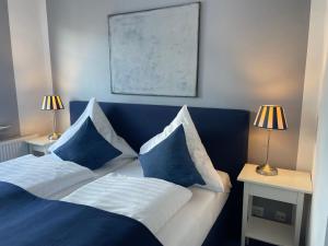 ein Schlafzimmer mit einem blauen und weißen Bett mit Kissen in der Unterkunft Hotel KAUP in Paderborn