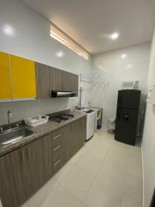 uma cozinha com armários castanhos e um frigorífico preto em Sachar Lodging Apartahotel em Bucaramanga
